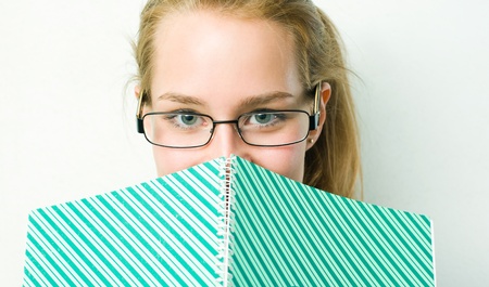 Beautiful young student girl peeking over her exercis book.の写真素材