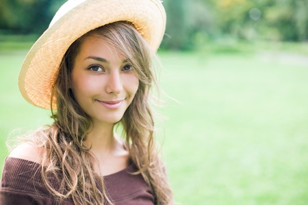 Portrait of gorgeous brunette posing in the park wearing straw hat.の写真素材