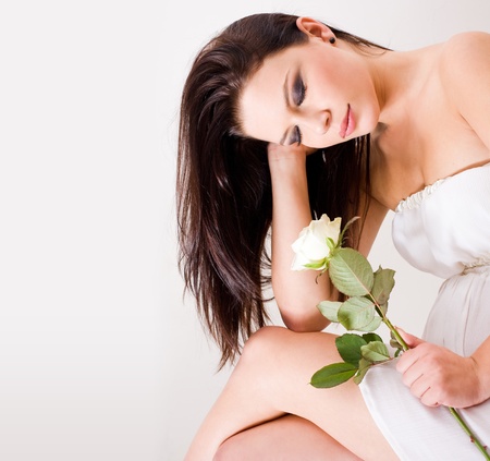Romantic portrait of beautiful brunette woman holding white rose.の写真素材