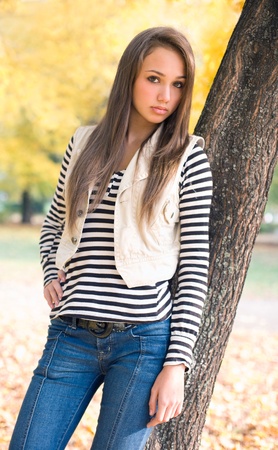 Beautiful slender young brunette model posing in the park.の写真素材