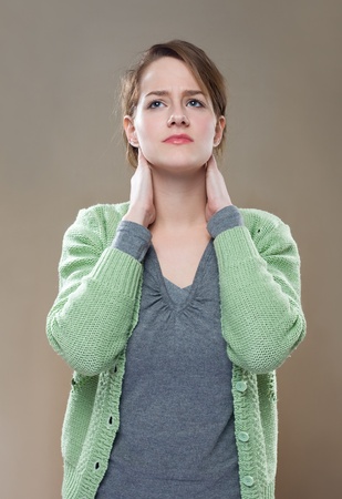 Porrait of fashionable young brunette woman showing symptoms of neck pain.の写真素材