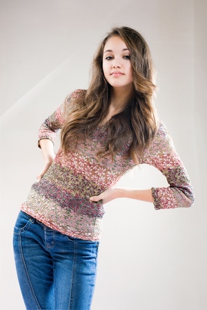 Portrait of fashionable young brunette girl in blue jeans and sweater.の写真素材