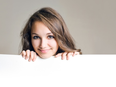 Beautiful young brunette girl holding blank white sign with copy space.の写真素材