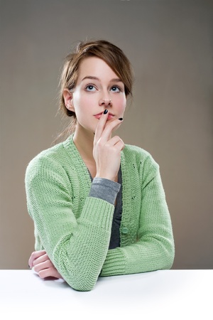 Beautiful young brunette woman sitting in pondering posture.の写真素材