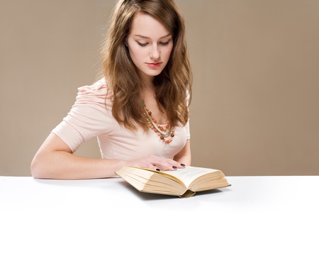 Beautiful young brunette woman reading a poem in a book.の写真素材