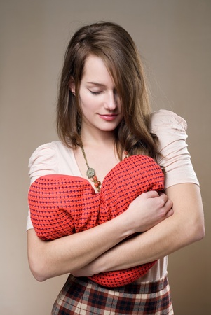 Gorgeous young brunette woman with heart shaped red pillow.の写真素材