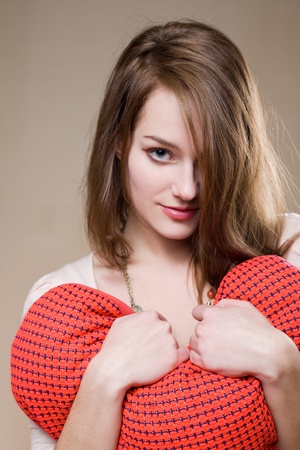 Gorgeous young brunette woman with heart shaped red pillow.の写真素材