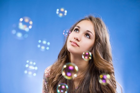 Portrait of a gorgeous young brunette teen admiring the soap bubbles.の写真素材