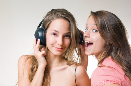 Two beautiful young brunette teens with exuberant expression and a headhone.の写真素材