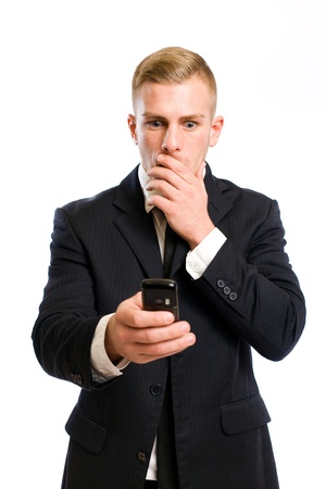 Elegant young businessman staring at his phone with shocked facial expression の写真素材