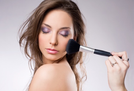 Portrait of a young brunette woman getting makeup, with brushes.の写真素材