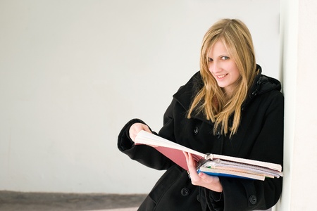 Half length portrait of a gorgeous young blond student girl holding colorful exercise books.の写真素材