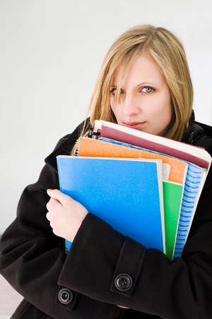 Outdoors portrait of a cute blond student girl holding exercise books.の写真素材