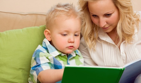 Portrait of a mother and son reading a book together at home.の写真素材