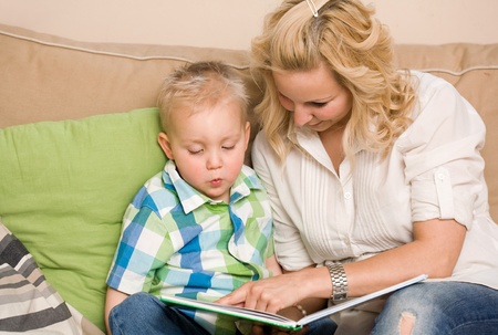 Attractive young mother reading a book with her son.の写真素材