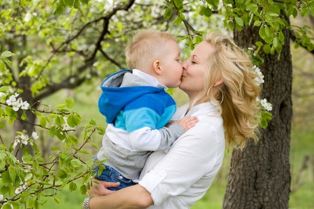 Pretty young mother getting a huge kiss from her baby son.の写真素材