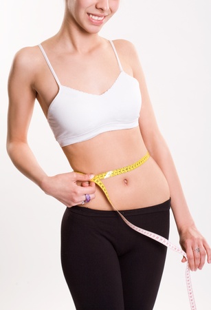 Slender smiling young brunette measuring her waistの写真素材