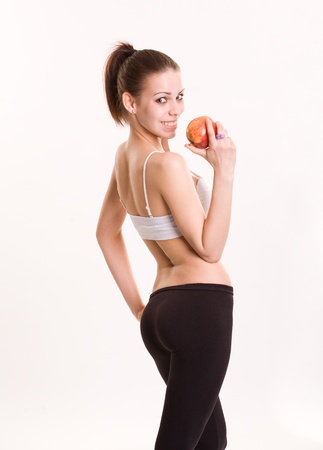 Cute slender young brunette fitness woman with red apple.の写真素材