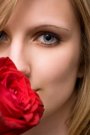 Moody portrait of elegant blonde with big vibrant red rose の写真素材