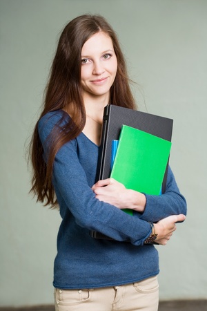 Portrait of a gorgeous young brunette student girl with laptop and exercis books.の写真素材