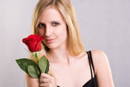 Portrait of a beautiful romantic young blond in elegant dress with red rose.の写真素材