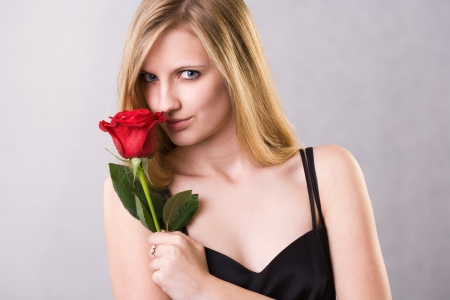 Romantic portrait of a gorgeous young blond woman holding big red rose.の写真素材