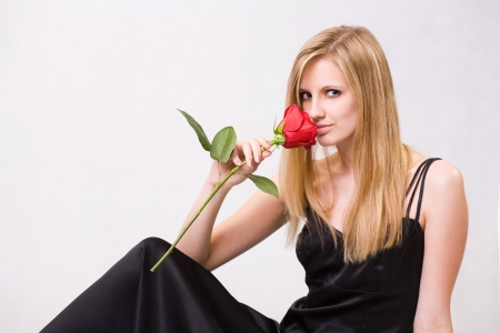 Romantic portrait of a gorgeous young blond woman holding big red rose.の写真素材
