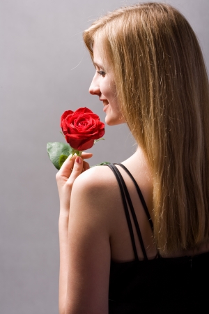 Portrait of a beautiful romantic young blond in elegant dress with red rose.の写真素材