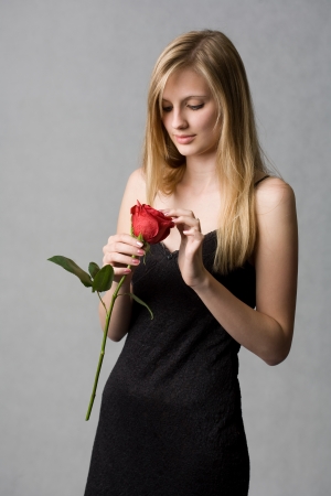 Romantic portrait of a gorgeous young blond woman holding big red rose.の写真素材