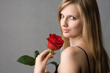 Portrait of a beautiful romantic young blond in elegant dress with red rose.の写真素材