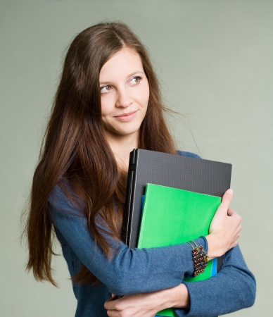 Portrait of a beautiful young student girl holding laptop.の写真素材