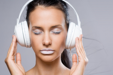 Dreamy young music lover, beautiful young brunette wearing big white headhones.の写真素材