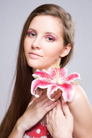 Beauty shot of young brunette woman with colorful flower and makeup.の写真素材