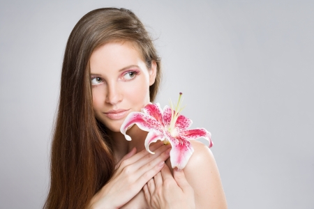 Gorgeous young bruinette beauty shot with colorful flower and makeup.の写真素材