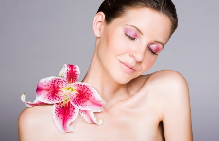 Beauty shot of young brunette woman with colorful flower and makeup.の写真素材