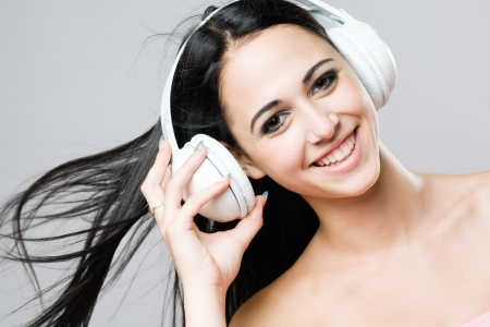Portrait of a brunette beauty enjoying music in white headphones の写真素材