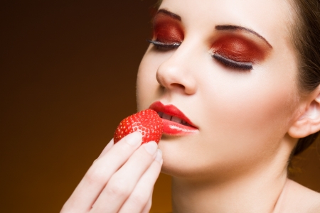 Sweet fruit craving, young brunette with strawberry.の写真素材