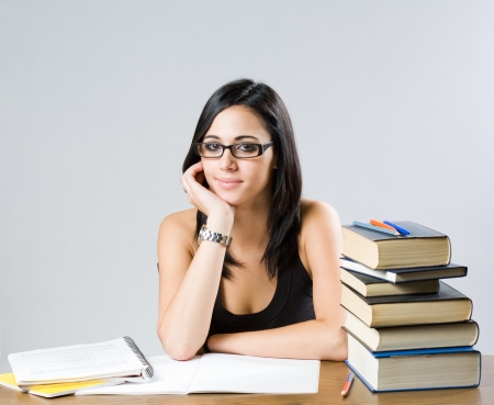 Portrait of a cute young brunette student girl with large pile of books.の写真素材