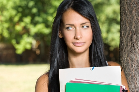 Outdoors portrait of a beautiful pondering thoughtful young student girl.の写真素材