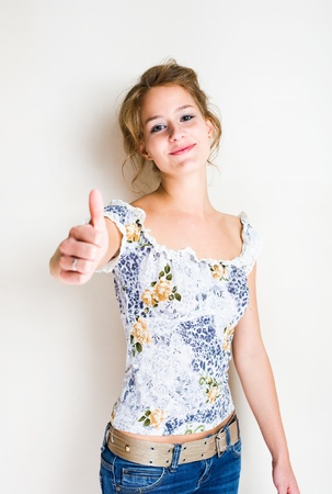Portrait of a young blond beauty showing big thumbs up.の写真素材