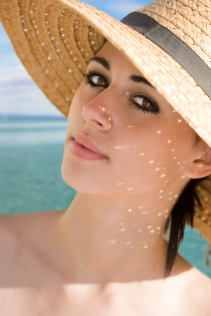 Relaxed summer, fashionable young brunette beauty in straw hat and sunshine.の写真素材