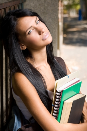 Portrait of an attractive young brunette student outdoors with exercise books.の写真素材