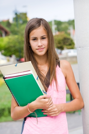 Portrait of a very cute young student girl outdoors with her exercise books.の写真素材