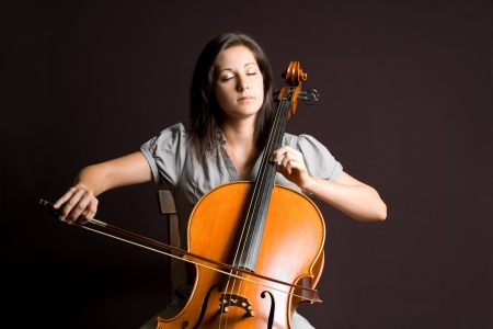 Portrait of beautiful young cellist immersed passionate in her music.