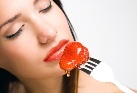 Portrait of a brunette beauty with honey dripping strawberry.の写真素材