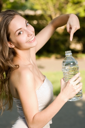 Very cheerful beautiful young brunette woman with clean bottled water.の写真素材