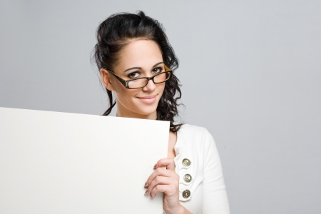 Portrait of a cute young brunette woman with white blank sign.の写真素材