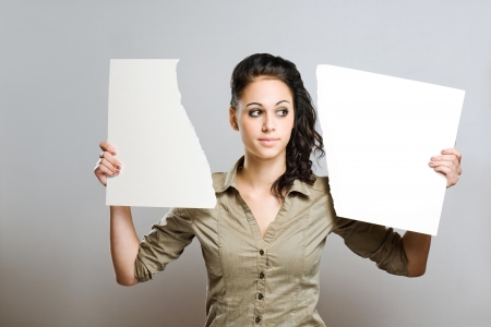Portrait of a gorgeous young brinette woman holding two halves of torn apart blank white billboad.の写真素材