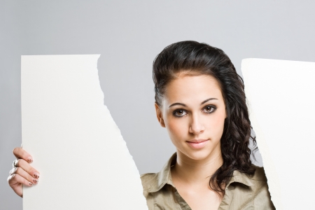 Beautiful young brunette woman tearing apart a white blank banner.の写真素材