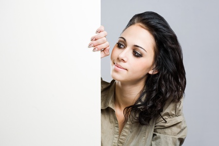 Portrait of an attractive young brunette woman holding blank billboard.の写真素材